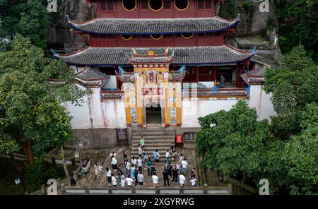 Chongqing. Juli 2024. Ein Drohnenfoto vom 10. Juli 2024 zeigt Menschen, die Shibaozhai besuchen, einen malerischen Ort im Zhongxian County im Südwesten Chinas in Chongqing. Shibaozhai sieht aus wie ein herzförmiger Bonsai, der mitten im Abschnitt der drei Schluchten von Yangtse Rier sitzt. Hier befindet sich eine 12-stöckige, 56 Meter hohe Holzpagode, die auf 20 Säulen steht und sich gegen die Klippe neigt. Dieses Gebäude stammt aus der Ming-Dynastie (1368–1644) und ist eine der wichtigsten Touristenattraktionen von Shibaozhai. Quelle: Liu Chan/Xinhua/Alamy Live News Stockfoto