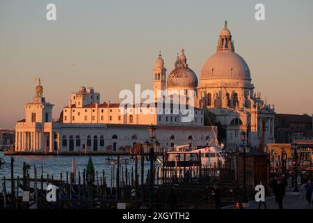 Punta della Dogana und Santa Maria della Salute fangen erste Sonnenstrahlen, Gondeln, die am Canale Grande in Venedig, Italien vertäut sind Stockfoto