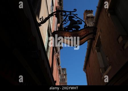 Blick auf das kunstvoll beleuchtete Schild für Trattoria Al Giardinetto da Severino mit seiner schmiedeeisernen Halterung und einem stehenden Löwen, der eine Kugel hält Stockfoto