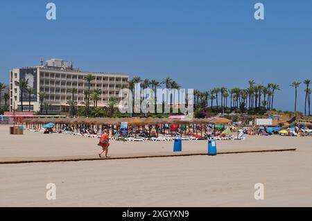 Touristen am Arenal Sandstrand im Sommer, mit dem Parador und Palmen dahinter, Xabia, Alicante, Spanien Stockfoto