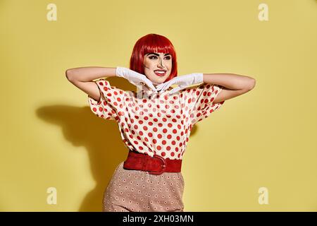 Lebendige rothaarige Frau mit kreativem Pop-Art-Make-up in einem Polka Dot-Shirt auf hellgelbem Hintergrund, das Comic-Charakter-Vibes ausstrahlt. Stockfoto