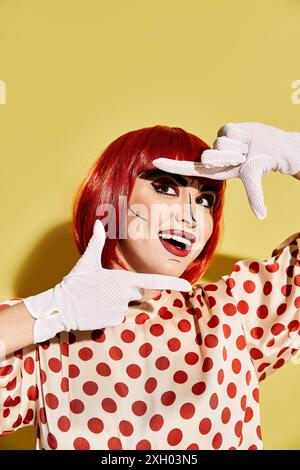 Eine hübsche rothaarige Frau mit dramatischem Pop Art Make-up und einer Polka Dot Bluse auf gelbem Hintergrund. Stockfoto