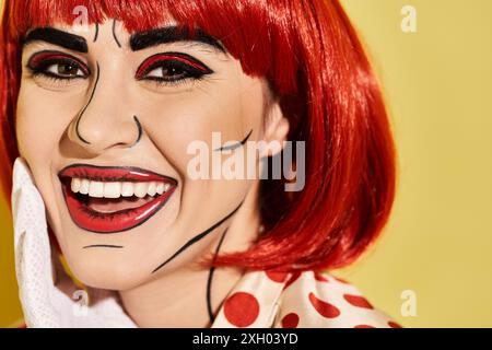 Eine hübsche rothaarige Frau mit kreativem Pop-Art-Make-up auf gelbem Hintergrund, die an eine Figur aus Comics erinnert. Stockfoto