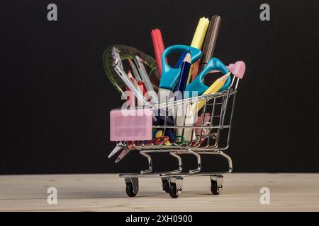 Back-to-School-Vorlage mit mehrfacher Schreibwaren im Wagen mit Kopierraum gegen Schwarz Stockfoto