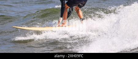 Nahaufnahme eines jungen Surfers Beine und Arme eines Surfers, der auf einer Welle reitet und vor der Küste von Long Island das Gleichgewicht sucht. Stockfoto