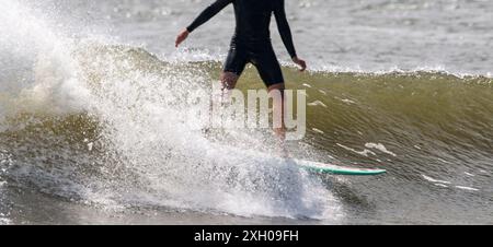 Nahaufnahme eines Mannes, der auf einer rauen Welle surft, in einem schwarzen, kurzen Neoprenanzug am Gilgo Beach von Long Island New York. Stockfoto