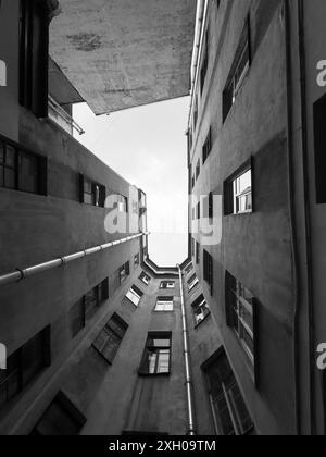 Schwarzweiß-Foto, das die dramatische Perspektive schmaler städtischer Wohngebäude mit einem klaren Blick auf den Himmel darüber feststellt. Stockfoto