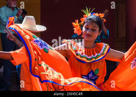 Granada, Nicaragua - 24. März 2019: Eine Tänzerin in einem leuchtend orangen Kleid feiert mit einem traditionellen Tanz. Stockfoto