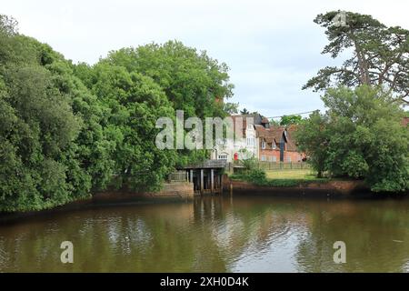 Beaulieu, Brockenhurst, England. 30. Juni 2024. National Motor Museum, Beaulieu. Beaulieu River, ein Blick auf die Landschaft mit einer Pause in den Bäumen mit Häusern dahinter. Stockfoto