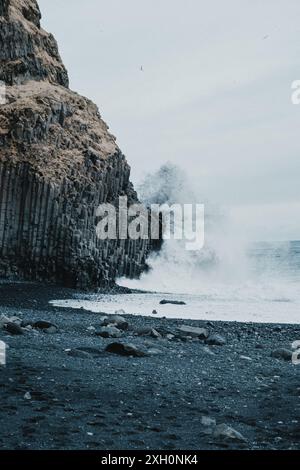 Wellen schlagen gegen die Basaltsäulen am Strand Reynisfjara an der Südküste Islands Stockfoto