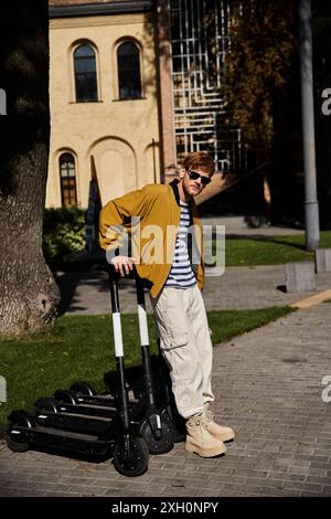 Junger rothaariger Mann in brauner Kleidung, der neben Motorrollern in der Stadt steht. Stockfoto