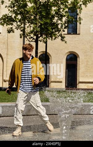 Junger rothaariger Mann in unbändiger Kleidung, der vor einem Wasserbrunnen steht. Stockfoto