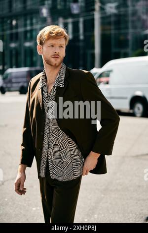 Ein junger rothaariger Mann, gekleidet in brauner Kleidung, steht selbstbewusst mitten in einer belebten Stadtstraße. Stockfoto