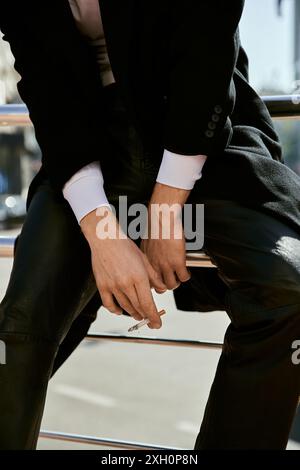 Ein stilvoller rothaariger Mann in formeller Kleidung, der allein auf einer Bank in einer Stadt sitzt. Stockfoto