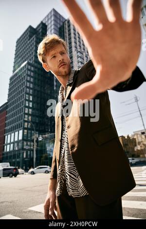 Junger rothaariger Mann in dämlicher Kleidung, der selbstbewusst auf einer Stadtstraße steht. Stockfoto