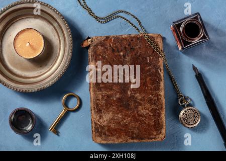 Ein altes Notizbuch mit Tintenstift, von oben mit anderen Vintage-Objekten aufgenommen, ein flaches lag auf blauem Hintergrund Stockfoto