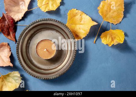 Herbst-Design-Vorlage mit Herbstblättern und einer Kerze, mit einem Platz für Text, von oben auf blauem Hintergrund aufgenommen Stockfoto