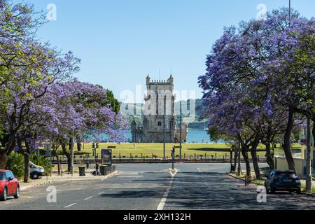 Belem Tower und Jacaranda blühende lila blaue Bäume am sonnigen Tag. Lissabon, Portugal. Stockfoto