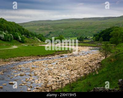 River Swale, malerische steile Hügel und Hänge (Wasser fließt, trockenes Sommerwetter, Kiesbett) - Swaledale, Yorkshire Dales, England Großbritannien. Stockfoto