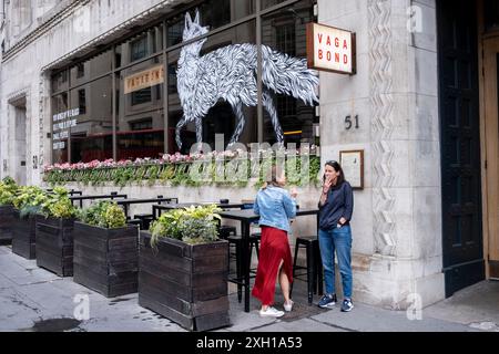 Fuchsmotiv im Fenster des Vagabond Weinladens und der Bar, während zwei Personen draußen Zigaretten rauchen am 2. Juli 2024 in London, Großbritannien. Stockfoto