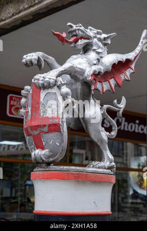 City of London Drachengrenze in einem Zustand der Verwerfung mit abblätternder Farbe in Barbican am 3. Juli 2024 in London, Großbritannien. Die Begrenzungszeichen der Drachen sind gusseiserne Statuen von Drachen auf Metall- oder Steinsockel, die die Grenzen der City of London markieren, mit silberfarbenen Details der Drachenflügel und der Zunge in Rot. Stockfoto