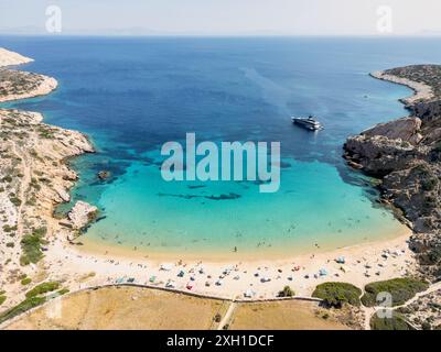 Eine abgeschiedene Bucht auf der griechischen Insel Donousa, mit türkisfarbenem Wasser, einem Sandstrand und einer einsamen Jacht vor Anker. Sonnenanbeter entspannen sich am Ufer, Stockfoto