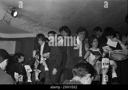 Die Rolling Stones unterzeichneten 1965 Autogramme auf der Bühne des Golf-Drouot in Paris. Henri Leproux, Gründer des Golf Drouot neben Mick Jagger (links). Jean-Claude Berthon, Direktor des Disco Revue Magazins am Mikrofon. Bill Wyman ist auf der rechten Seite. Stockfoto