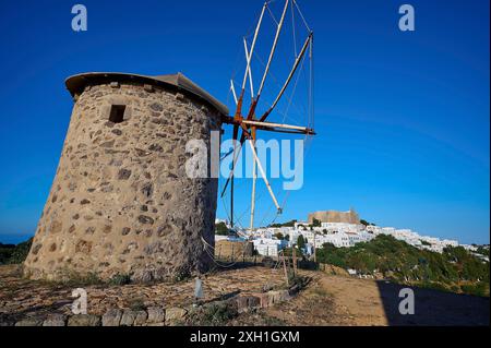 Steinwindmühle vor einem klaren blauen Himmel mit einem Dorf und einer natürlichen Kulisse, Windmühlen, auf einem Kamm, oberhalb von Chora, Hauptstadt Patmos, Patmos, alt Stockfoto
