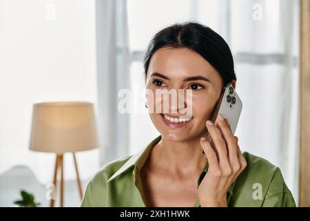 Eine Frau in lässiger Kleidung spricht auf einem Handy in einem gemütlichen Wohnzimmer. Stockfoto