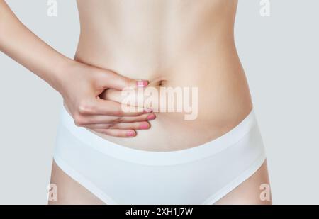 Eine Frau zeigt Körperfett auf ihrem Bauch. Ubergewicht und sportlicher Lebensstil. Kosmetologiekonzept. Stockfoto