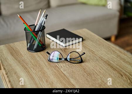 Ein Holztisch mit einer Tasse Bleistifte und einer Brille. Stockfoto