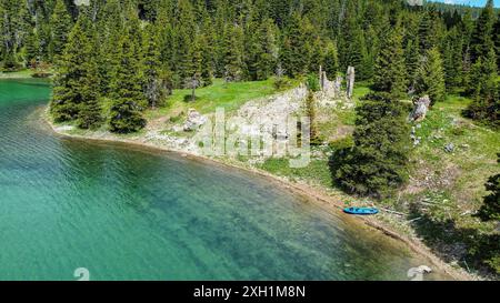 Aus der Vogelperspektive eines Kajaks auf dem wunderschönen blaublauen Wasser des Crystal Lake, umgeben von Kiefern. Lewis and Clark National Forest, Montana Stockfoto