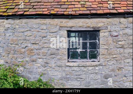 Altes Holzfenster in einem Backsteingebäude mit rotem Ziegeldach Stockfoto