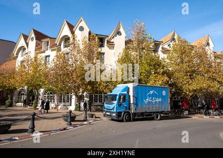 Typische Häuser der Stadt Ifrane im Mittleren Atlas in Marokko, Nordafrika. Ein Transporter mit natürlichem Mineralwasser auf der Straße Stockfoto