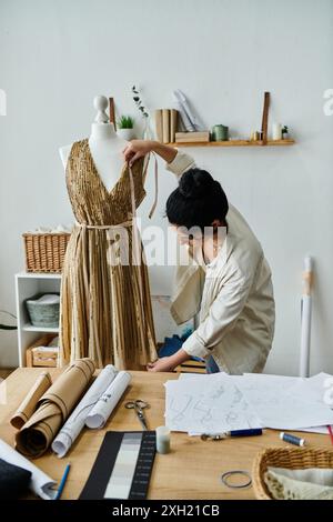 Eine junge Frau, die ihre Kleidung aufrüttelt und ein Kleid auf einem Tisch entwirft. Stockfoto