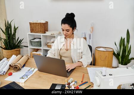 Frau in lässiger Kleidung bringt Kleidung auf Laptop für umweltfreundliche Mode auf. Stockfoto