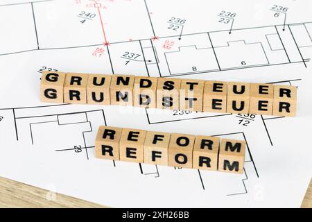 Symbolbild der Grundsteuerreform: Buchstabenwürfel auf einem Bebauungsplan zeigen das deutsche Wort GRUNDSTEUERREFORM (Grundsteuerreform) Stockfoto