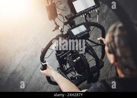 Filmemacher, Kamera und Mann im Studio für Fotografie, Produktion und Medien. Hinter den Kulissen, hinter der Bühne und Person mit Stabilisierung Stockfoto