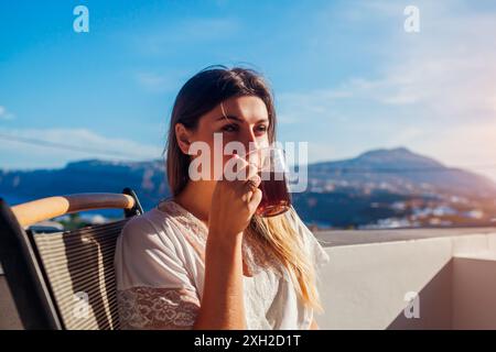 Frau, die sich auf der Hotelterrasse entspannt und morgens Kaffee trinkt und die Berglandschaft genießt. Frühstück mit Aussicht. Sommerurlaub Stockfoto