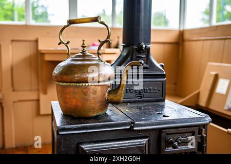 Vintage-Kupferkessel auf einem klassischen Holzofen in gemütlicher rustikaler Küche. Stockfoto