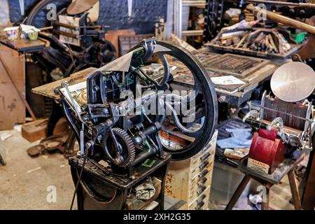 Vintage-Druckmaschine in einer alten Werkstatt, in der komplizierte Zahnräder und Maschinen für die traditionelle Druckerei präsentiert werden. Stockfoto