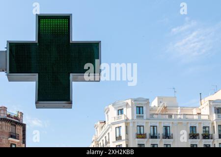 Indikationszeichen für Apotheke, ein leuchtendes grünes Kreuz, das anzeigt, dass eine Apotheke geöffnet ist und Dienstleistungen erbringt. Stockfoto