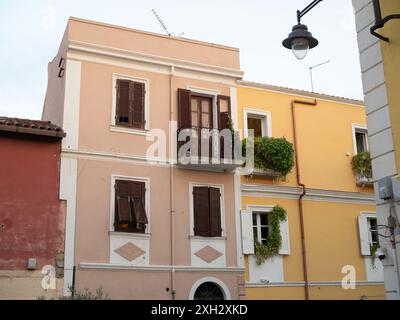 Altstadt von Olbia: Eine horizontale Aufnahme zweistöckiger italienischer Häuser in drei Farben: Terrakotta, Pastellrosa und leuchtendes Gelb. Stockfoto