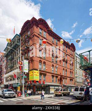 NYC Chinatown: Aufwendige Terrakotta kleidet Fenster, Eingang und Gesimse eines begehbaren Wohngebäudes aus roten Backsteinen über dem chinesischen Restaurant. Stockfoto