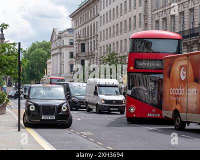 London, England - 02. Juni 2024: Londoner Verkehr mit geparktem schwarzen Taxi und rotem Stadtbus, der in der Hauptverkehrszeit die Fahrspur wechselt Stockfoto