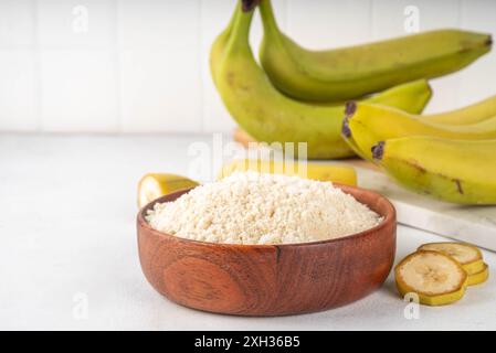 Alternatives Bio-Bananenmehl mit frischen ganzen und in Scheiben geschnittenen grünen Bananen auf weißem Tischhintergrund Stockfoto