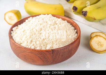 Alternatives Bio-Bananenmehl mit frischen ganzen und in Scheiben geschnittenen grünen Bananen auf weißem Tischhintergrund Stockfoto