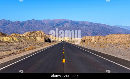 Desert Road - Ein weiter Blick auf den neu renovierten State Highway 190, der sich in Richtung zerklüfteter violetter Berge erstreckt. Death Valley National Park, CA, USA. Stockfoto