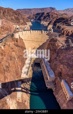 Hoover Dam – Ein vertikaler Überblick über den Hoover Dam, der an einem hellen, sonnigen Wintertag mit roten Felswänden des Black Canyon des Colorado River verschmolzen ist. NV - AZ, USA. Stockfoto