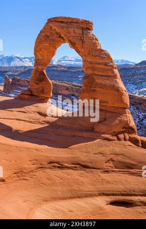 Winter Delicate Arch - Nahaufnahme des Delicate Arch mit schneebedeckten La Sal Mountains im Hintergrund an einem klaren, sonnigen Wintertag. Stockfoto